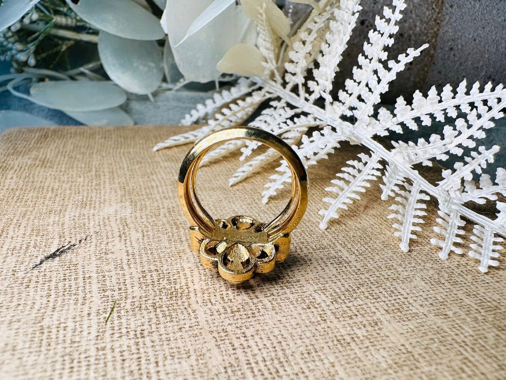 This vintage emerald green and pearl gold cocktail ring is such a pretty piece. Vintage Avon from the 1976 Versailles collection. Green, pearls and gold are a beautiful color combination. The center faceted oval green stone is surrounded in a raised filigree design that is full of vintage character, with two tiny pearl cabochon accents. Signed in excellent vintage condition. 