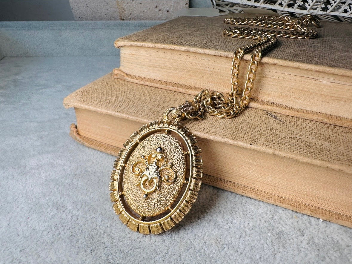 This 1970s vintage Victorian Revival cameo necklace is marvelous. Bold, yet elegant this classic necklace features a double sided reversible cameo pendant. On one side is the portrait of a lady in cream and classic muted orange and on the other side an ornate Fleur de Lis raised in gold. This vintage necklace features a medium width antique gold curb chain, from 1974. In great vintage condition please view all pics. Would look incredible in a necklace stack for a modern twist.