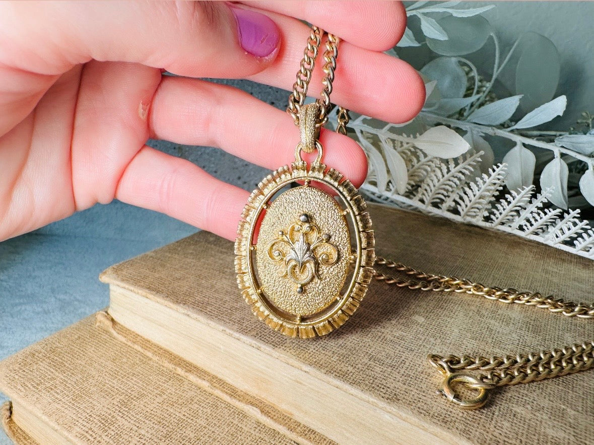 This 1970s vintage Victorian Revival cameo necklace is marvelous. Bold, yet elegant this classic necklace features a double sided reversible cameo pendant. On one side is the portrait of a lady in cream and classic muted orange and on the other side an ornate Fleur de Lis raised in gold. This vintage necklace features a medium width antique gold curb chain, from 1974. In great vintage condition please view all pics. Would look incredible in a necklace stack for a modern twist.