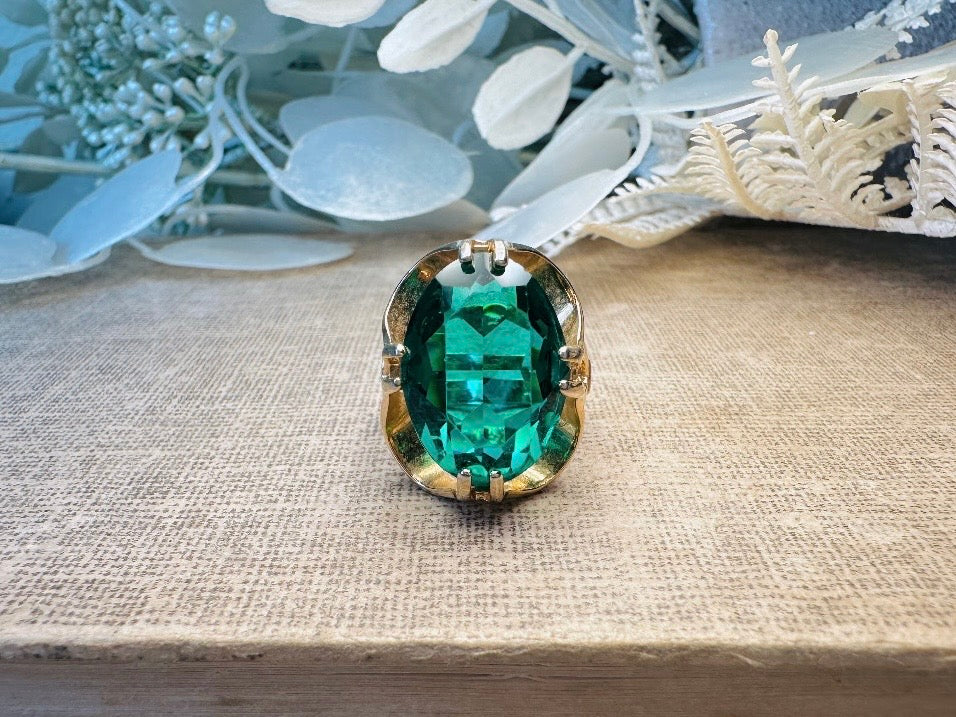 Green gemstone pendant on a textured surface with decorative elements in the background