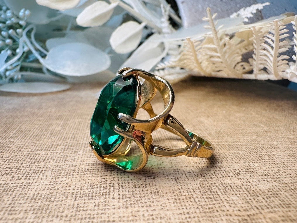 Gold ring with a green gemstone on a textured surface