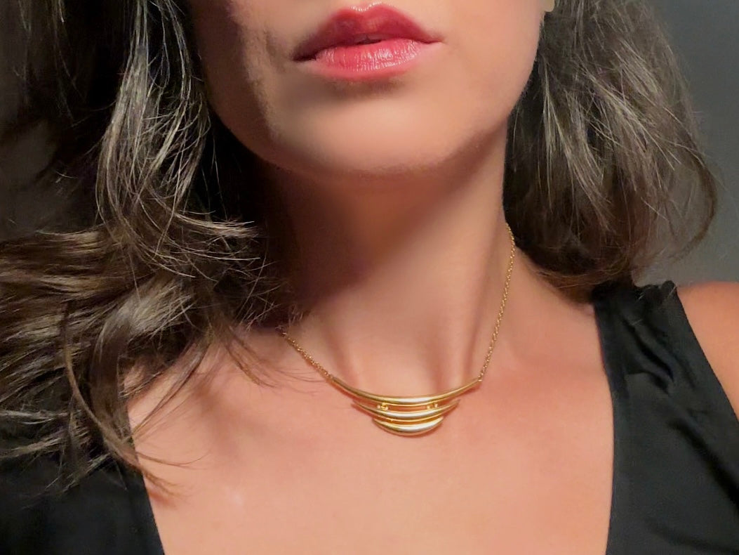 This vintage Crown Trifari triple gold bar necklace is a beauty. From the 1960s this dainty short style choker necklace looks beautiful alone or paired with others for a fantastic stack. The fine gold plated chain suspends a small gold pendant composed of 3 curved bars in graduated size- signed on back and with the signature Trifari hang tag.
