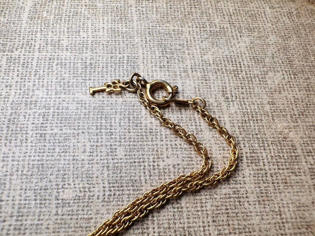 This vintage Crown Trifari triple gold bar necklace is a beauty. From the 1960s this dainty short style choker necklace looks beautiful alone or paired with others for a fantastic stack. The fine gold plated chain suspends a small gold pendant composed of 3 curved bars in graduated size- signed on back and with the signature Trifari hang tag.