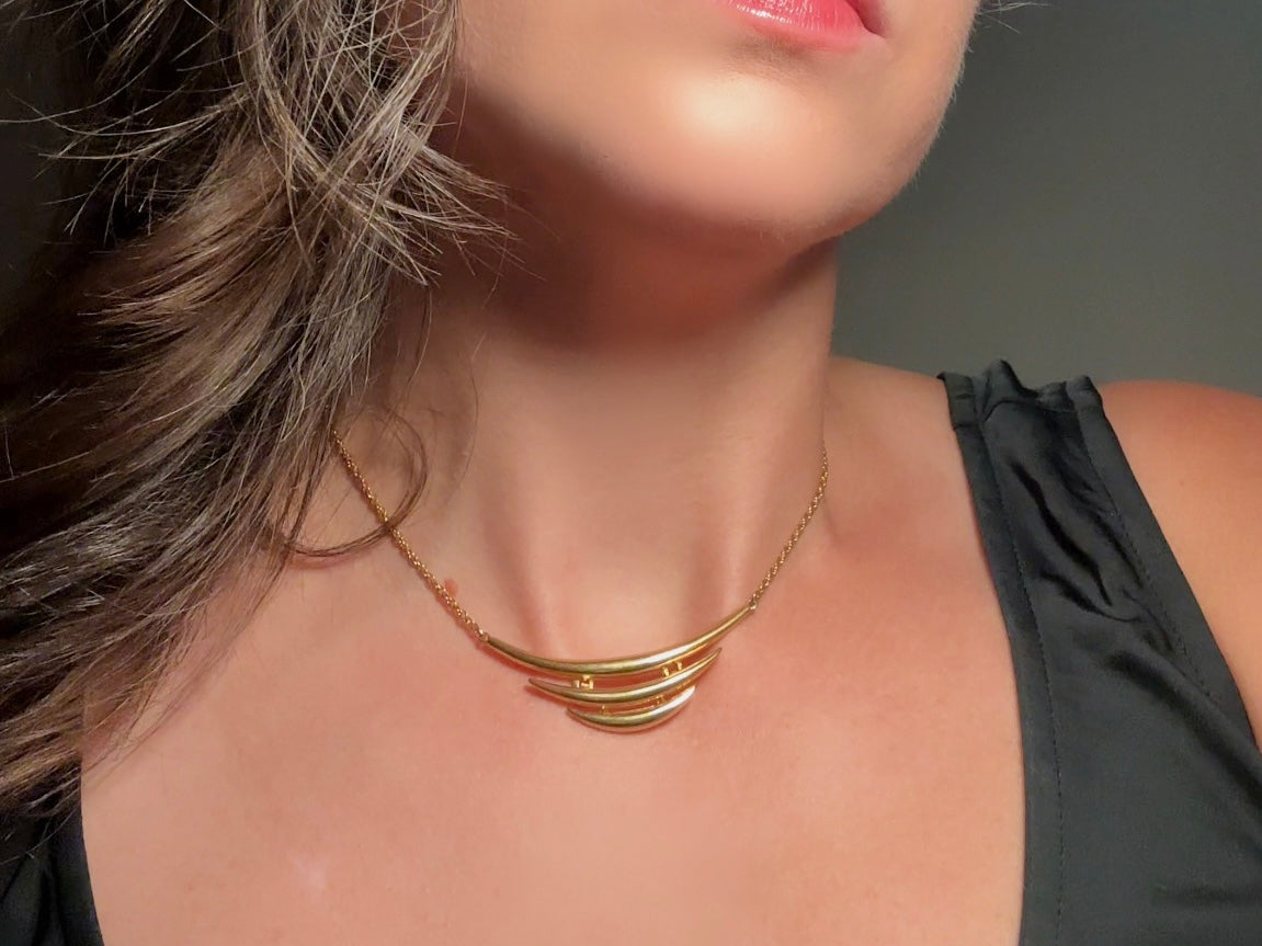 This vintage Crown Trifari triple gold bar necklace is a beauty. From the 1960s this dainty short style choker necklace looks beautiful alone or paired with others for a fantastic stack. The fine gold plated chain suspends a small gold pendant composed of 3 curved bars in graduated size- signed on back and with the signature Trifari hang tag.