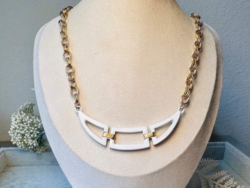 This white and gold vintage geometric necklace is chic and unique. Double link gold curb chain connects with a white geometric pendant bib, comprised or three white enameled articulated pieces. Versatile while making a statement. Minimal wear and in great vintage condition. A perfect summer necklace to incorporate into a variety of looks, paired with others or worn alone.
Dimensions: 18" long