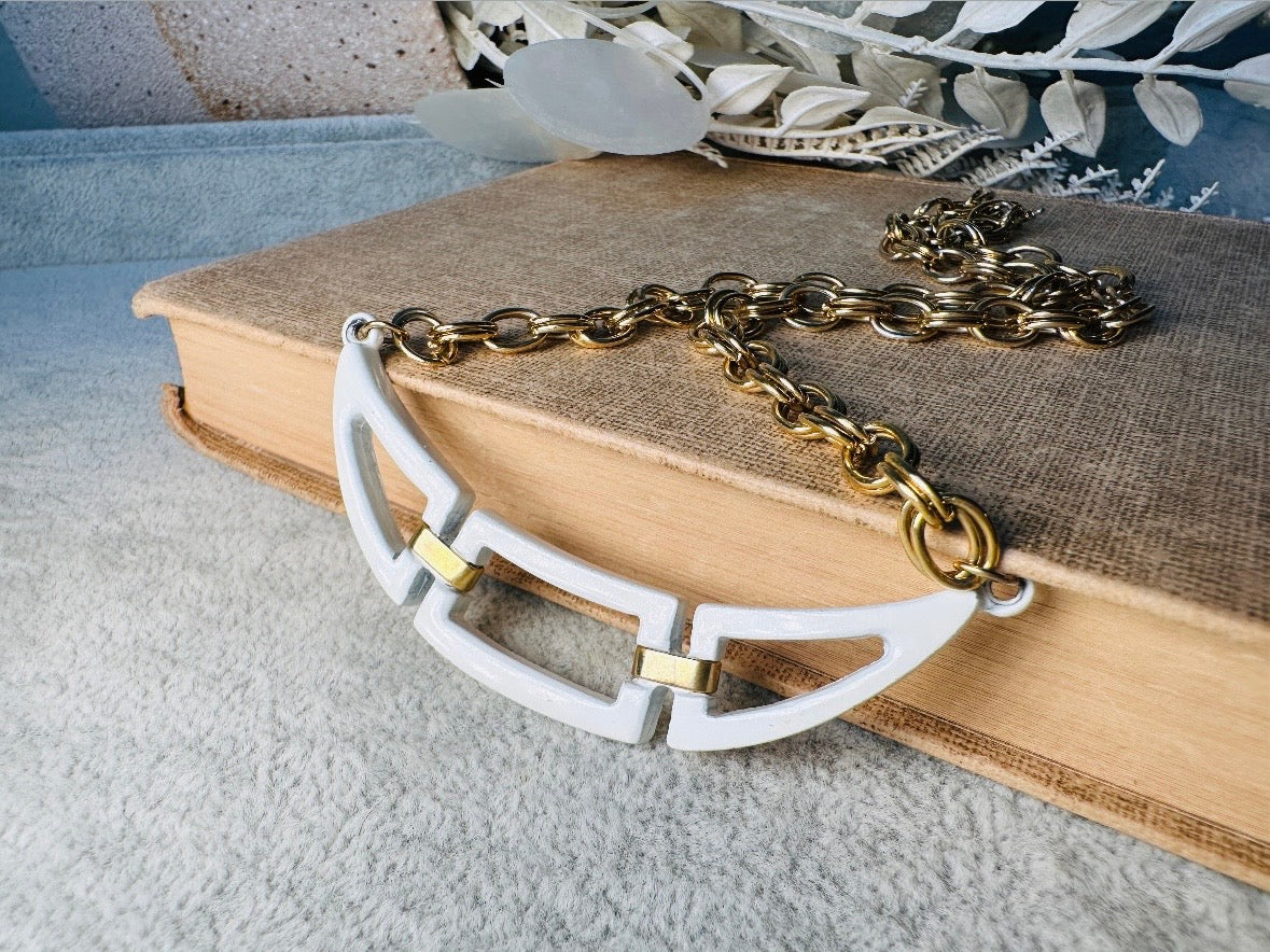 This white and gold vintage geometric necklace is chic and unique. Double link gold curb chain connects with a white geometric pendant bib, comprised or three white enameled articulated pieces. Versatile while making a statement. Minimal wear and in great vintage condition. A perfect summer necklace to incorporate into a variety of looks, paired with others or worn alone.
Dimensions: 18" long