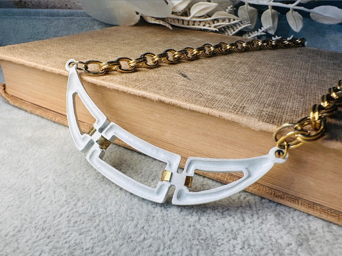 This white and gold vintage geometric necklace is chic and unique. Double link gold curb chain connects with a white geometric pendant bib, comprised or three white enameled articulated pieces. Versatile while making a statement. Minimal wear and in great vintage condition. A perfect summer necklace to incorporate into a variety of looks, paired with others or worn alone.
Dimensions: 18" long