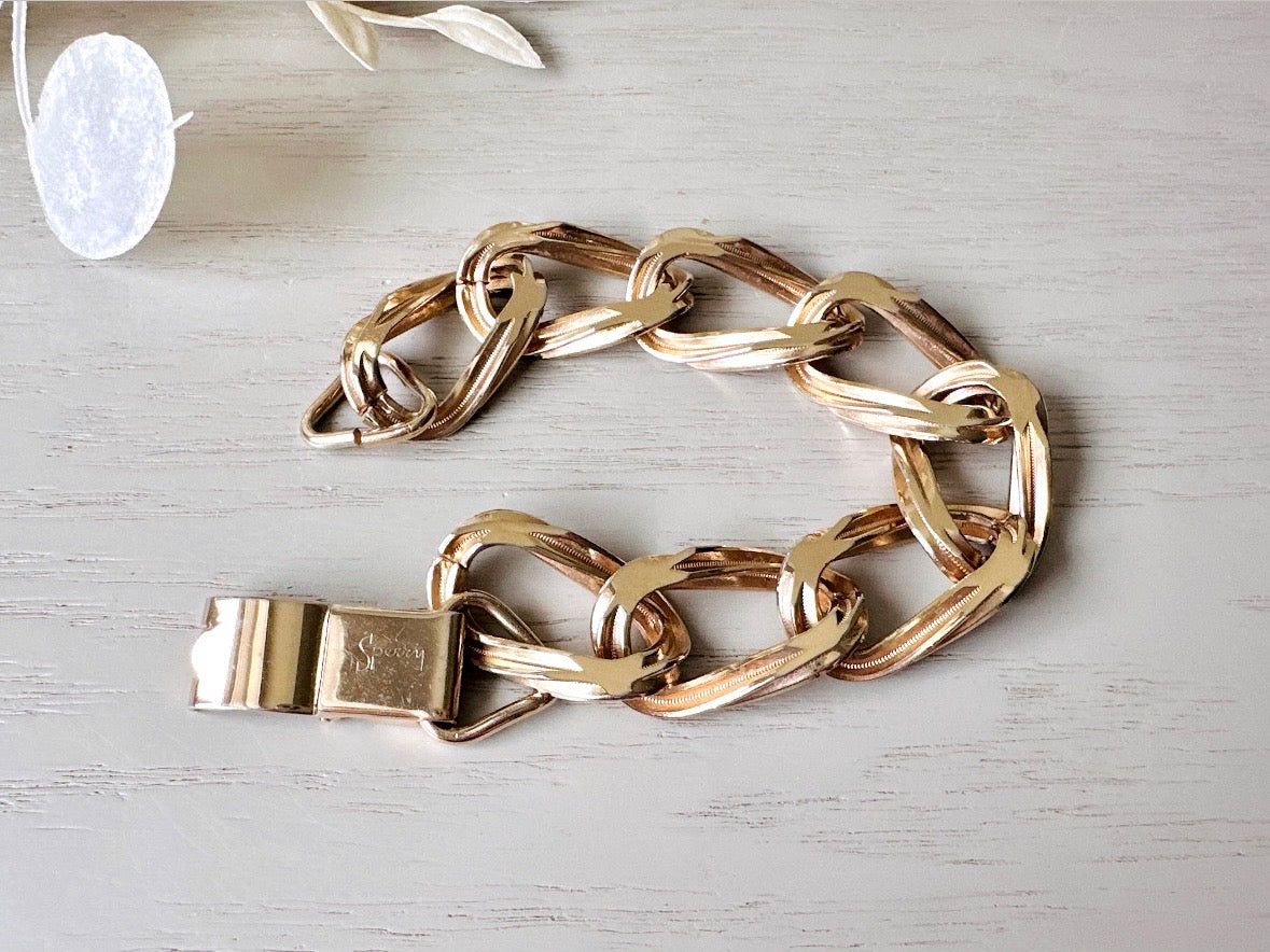 This vintage gold chain 1970s bracelet is beautiful. A signed Sperry piece- this company was renowned for elegant and well crafted chain jewelry. This chain bracelet is so unique- the wide width curb chain has an intricate dotted border as it weaves and links with the next. A gorgeous light gold shade and in fantastic vintage condition, no major flaws to note. Hinge clip clasp. Looks amazing paired with others for the ultimate stack!