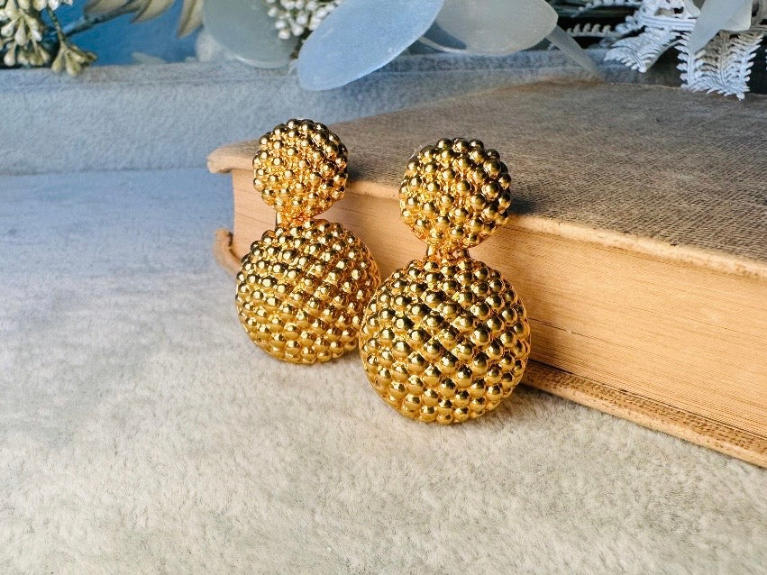These vintage gold statement earrings are absolutely fabulous! Gold tone double dome drop earrings are chock full of interesting details. These earrings feature 2 large dome shaped gold components with a dotted "raspberry" texture- just so stunning! These earrings are such a classic 80s pair- bold and dramatic! In great vintage condition -no major flaws to note- please see pics. Signed Avon- pierced style!