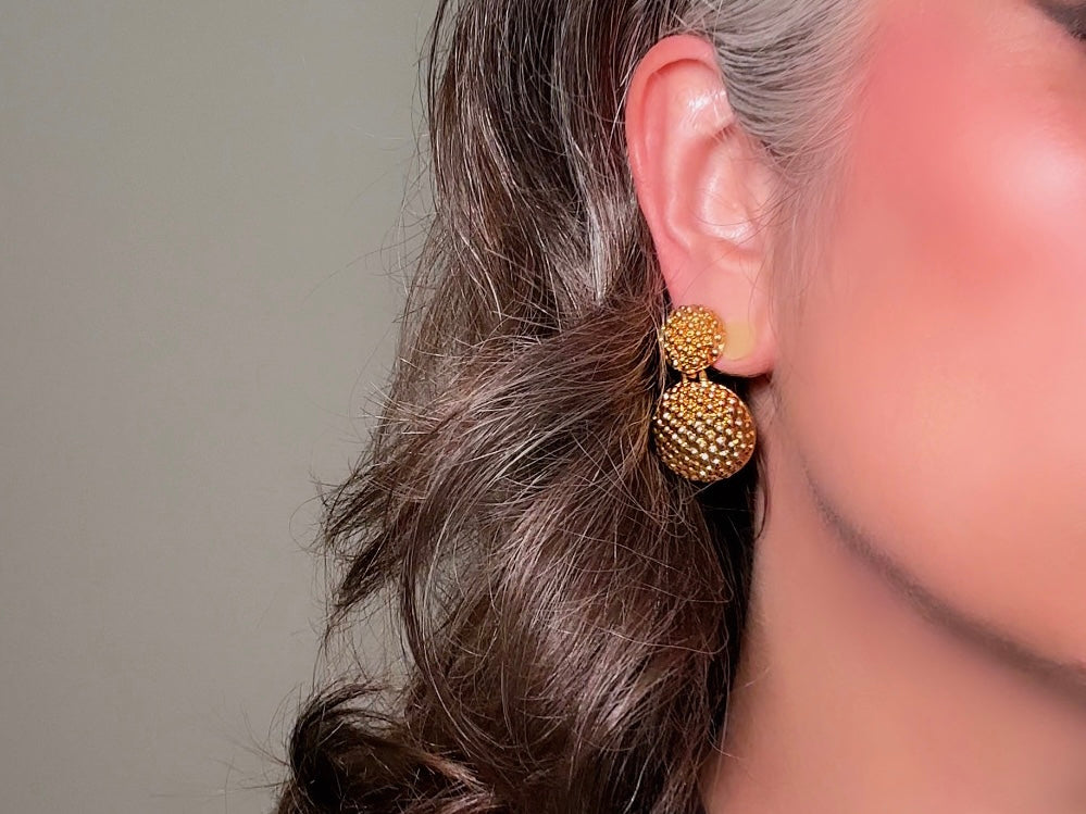 These vintage gold statement earrings are absolutely fabulous! Gold tone double dome drop earrings are chock full of interesting details. These earrings feature 2 large dome shaped gold components with a dotted "raspberry" texture- just so stunning! These earrings are such a classic 80s pair- bold and dramatic! In great vintage condition -no major flaws to note- please see pics. Signed Avon- pierced style!