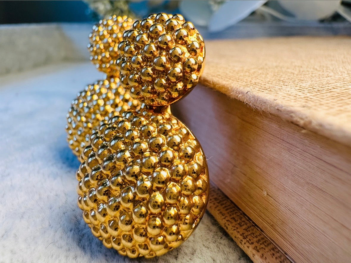 These vintage gold statement earrings are absolutely fabulous! Gold tone double dome drop earrings are chock full of interesting details. These earrings feature 2 large dome shaped gold components with a dotted "raspberry" texture- just so stunning! These earrings are such a classic 80s pair- bold and dramatic! In great vintage condition -no major flaws to note- please see pics. Signed Avon- pierced style!
