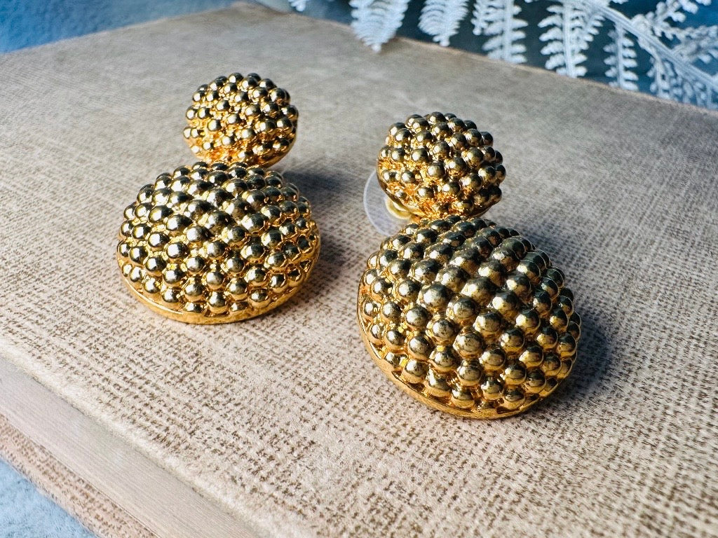 These vintage gold statement earrings are absolutely fabulous! Gold tone double dome drop earrings are chock full of interesting details. These earrings feature 2 large dome shaped gold components with a dotted "raspberry" texture- just so stunning! These earrings are such a classic 80s pair- bold and dramatic! In great vintage condition -no major flaws to note- please see pics. Signed Avon- pierced style!