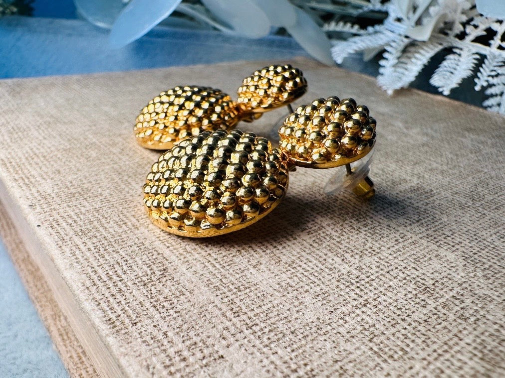These vintage gold statement earrings are absolutely fabulous! Gold tone double dome drop earrings are chock full of interesting details. These earrings feature 2 large dome shaped gold components with a dotted "raspberry" texture- just so stunning! These earrings are such a classic 80s pair- bold and dramatic! In great vintage condition -no major flaws to note- please see pics. Signed Avon- pierced style!