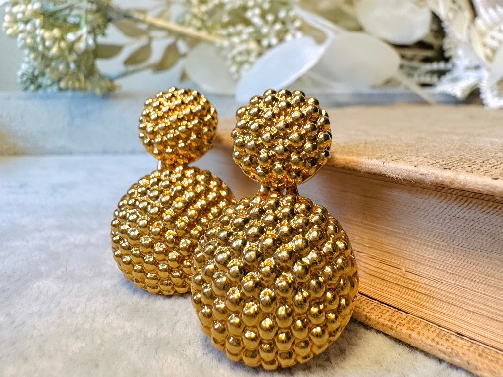 These vintage gold statement earrings are absolutely fabulous! Gold tone double dome drop earrings are chock full of interesting details. These earrings feature 2 large dome shaped gold components with a dotted "raspberry" texture- just so stunning! These earrings are such a classic 80s pair- bold and dramatic! In great vintage condition -no major flaws to note- please see pics. Signed Avon- pierced style!