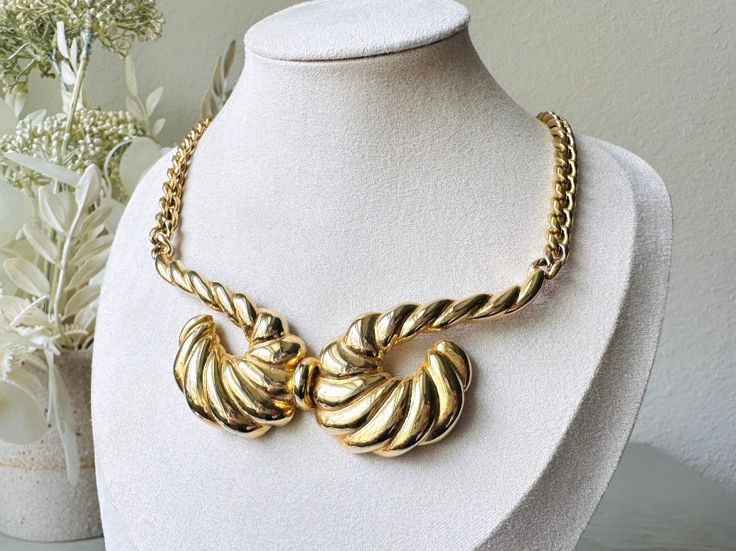 This 1970s vintage gold necklace is such a striking and unique piece. Featuring gold curb chain and a striking centerpiece of two textured gold horns. Full of vintage flair, this centerpiece is dimensional and stunning. This choker necklace is so flattering on and the perfect collar length. An excellent gift for the vintage lover in your life (especially if that's you!).