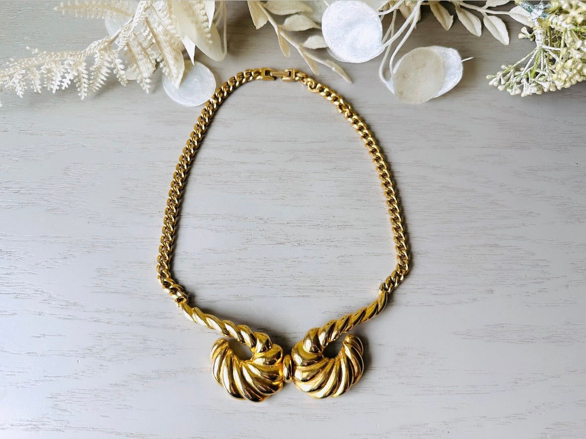 This 1970s vintage gold necklace is such a striking and unique piece. Featuring gold curb chain and a striking centerpiece of two textured gold horns. Full of vintage flair, this centerpiece is dimensional and stunning. This choker necklace is so flattering on and the perfect collar length.