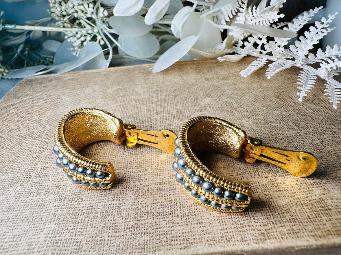 These oversized gold hoop vintage statement earrings feature two rows of chanel set dark silver pearls in graduating size, the sides are a beautiful roped texture. These dark silver pearl and gold half hoop earrings are huggie hoop style- these clip ons effortlessly add a touch of bold glam the 80s are so beloved for. A beautiful textured finish, the contrast of cool silver pearls and classic gold- these earrings are a showstopping vintage pair, in excellent condition.