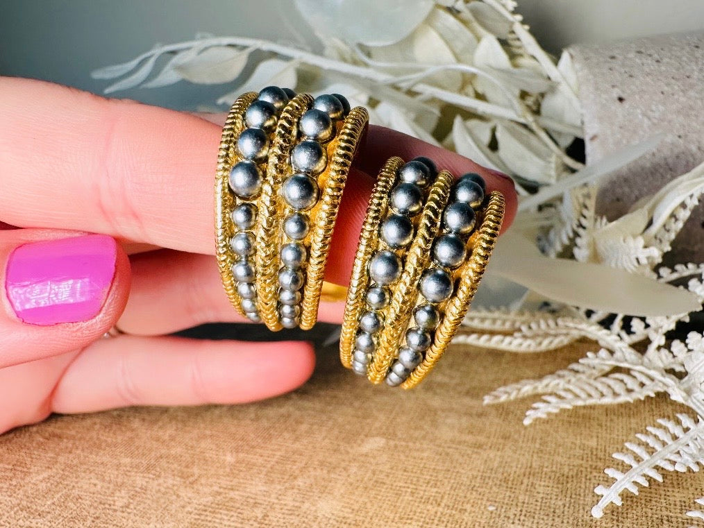 These oversized gold hoop vintage statement earrings feature two rows of chanel set dark silver pearls in graduating size, the sides are a beautiful roped texture. These dark silver pearl and gold half hoop earrings are huggie hoop style- these clip ons effortlessly add a touch of bold glam the 80s are so beloved for. A beautiful textured finish, the contrast of cool silver pearls and classic gold- these earrings are a showstopping vintage pair, in excellent condition.