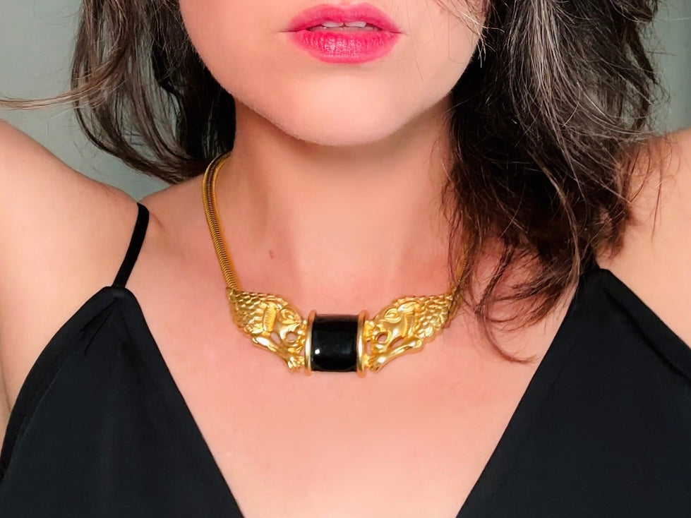 This bold vintage Etruscan style double lion necklace is truly incredible. Featuring two intricate sculptural gold lions on either side of a black enamel focal. This vintage collar necklace is the height of 80s glam, with its contrasting shiny black enamel and matte satin gold components. Wide snake chain and an oversized clasp complete this sensational necklace.