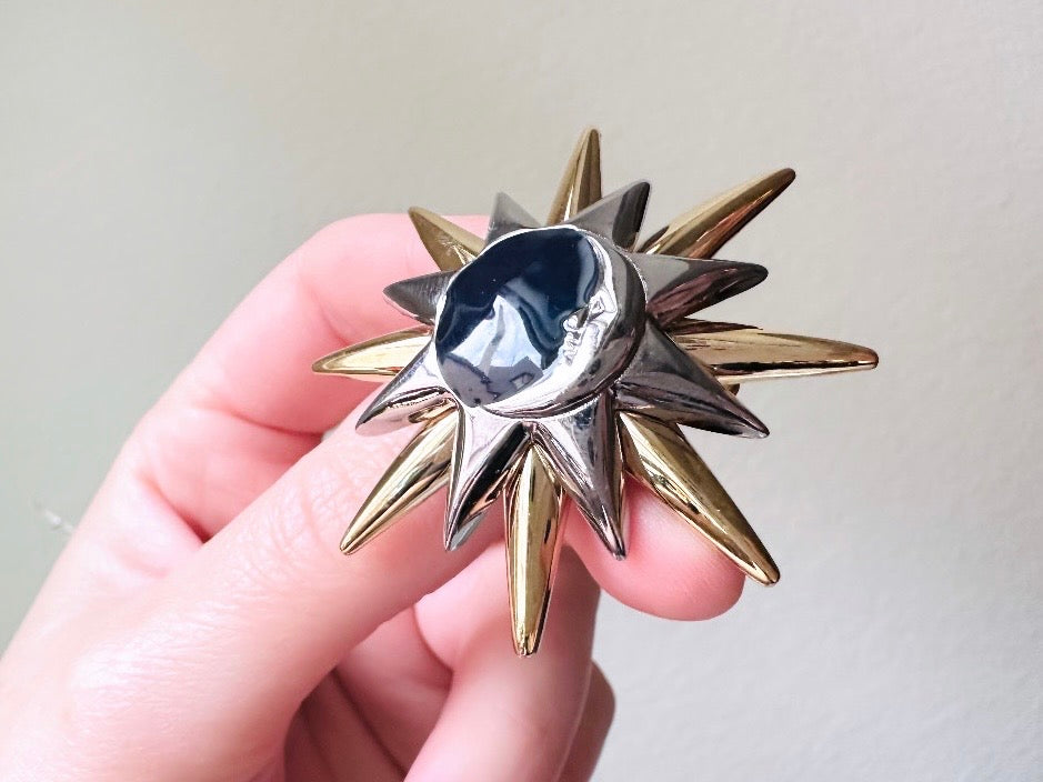 This is a vintage Liz Claiborne moon and starburst brooch from the 1980s. In excellent condition, this pin features a silver and gold starburst with a silver crescent moon on top of black circular enamel inlay. High quality designer signed brooch. No flaws to note, this vintage brooch has a fully working pin and lock, in great condition. Held in hand.