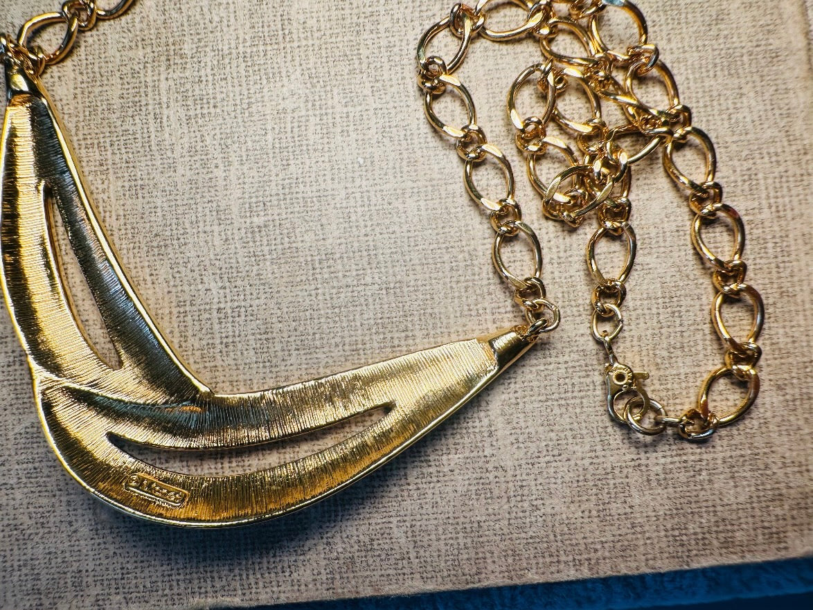 This cream and gold Monet vintage necklace is a striking classic. The focal pendant is an abstract asymmetrical crescent in gold with creamy enamel and sleek cut outs. This vintage designer necklace features gold cable chain and a signature Monet clasp and tag, also signed on back. This is a spectacular modernist jewelry piece to layer and easily goes with a variety of styles. Monet is renowned and well loved for beautiful jewelry that has stood the test of time. Excellent vintage condition, no flaws to not