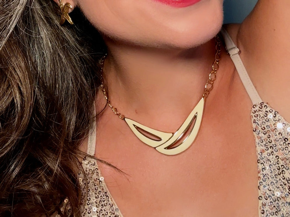 This cream and gold Monet vintage necklace is a striking classic. The focal pendant is an abstract asymmetrical crescent in gold with creamy enamel and sleek cut outs. This vintage designer necklace features gold cable chain and a signature Monet clasp and tag, also signed on back. This is a spectacular modernist jewelry piece to layer and easily goes with a variety of styles. Monet is renowned and well loved for beautiful jewelry that has stood the test of time. Excellent vintage condition, no flaws to not