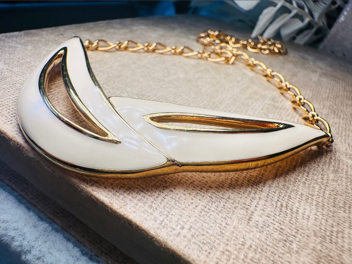 This cream and gold Monet vintage necklace is a striking classic. The focal pendant is an abstract asymmetrical crescent in gold with creamy enamel and sleek cut outs. This vintage designer necklace features gold cable chain and a signature Monet clasp and tag, also signed on back. This is a spectacular modernist jewelry piece to layer and easily goes with a variety of styles. Monet is renowned and well loved for beautiful jewelry that has stood the test of time. Excellent vintage condition, no flaws to not