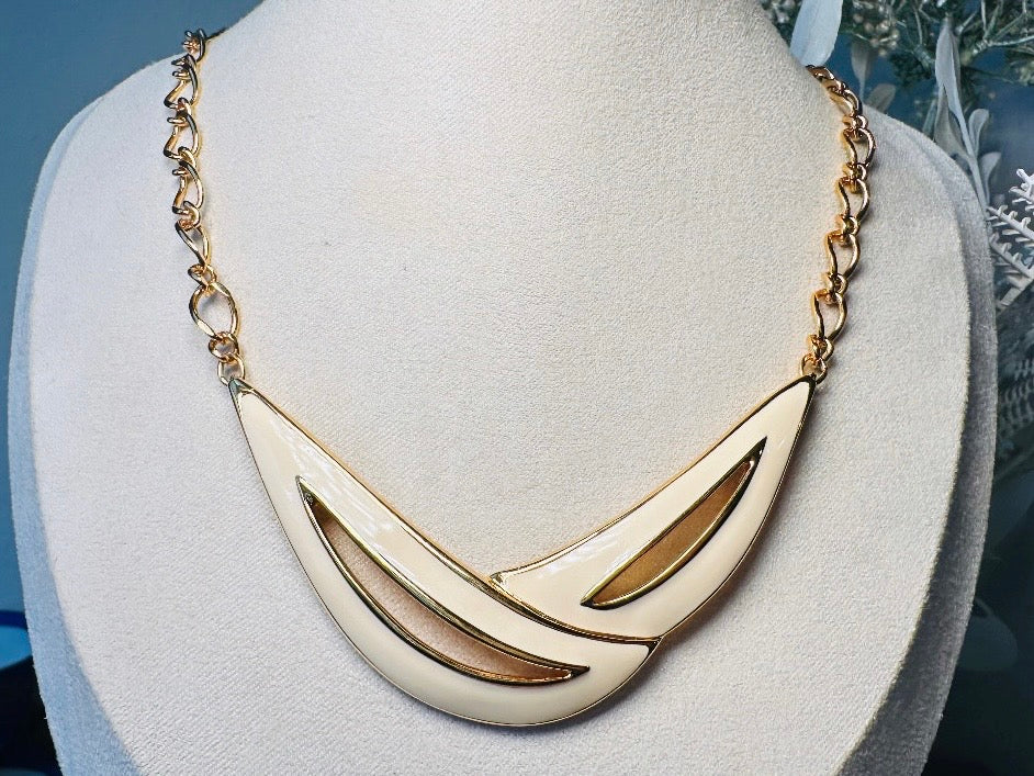 This cream and gold Monet vintage necklace is a striking classic. The focal pendant is an abstract asymmetrical crescent in gold with creamy enamel and sleek cut outs. This vintage designer necklace features gold cable chain and a signature Monet clasp and tag, also signed on back. This is a spectacular modernist jewelry piece to layer and easily goes with a variety of styles. Monet is renowned and well loved for beautiful jewelry that has stood the test of time. Excellent vintage condition, no flaws to not