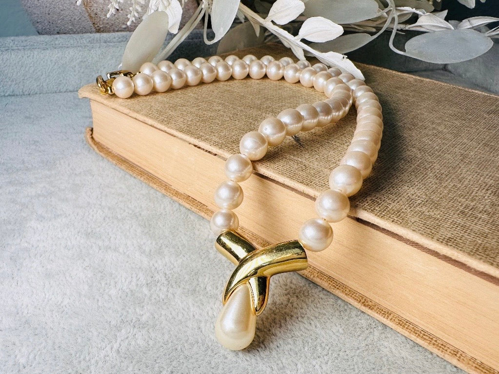This vintage Napier pearl pendant necklace is stunning. From the 1980s this necklace is sleek and interesting, featuring 8mm cream pearls with a gold twist and cream pearl teardrop pendant. Fold over clasp with Napier signature. Would look beautiful on a bride or stacked with some chains for a modern spin. In excellent vintage condition.