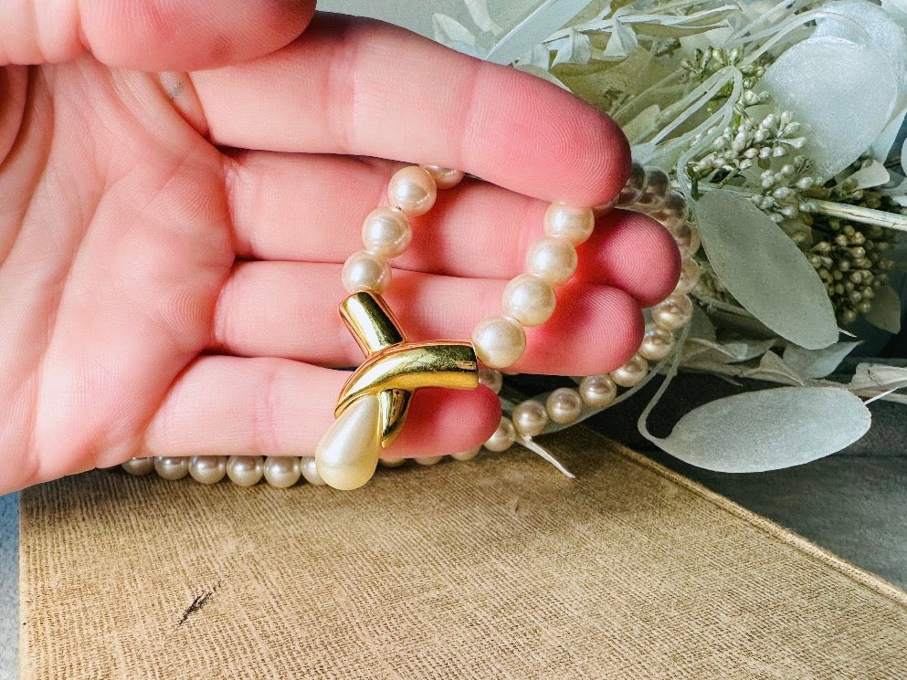 This vintage Napier pearl pendant necklace is stunning. From the 1980s this necklace is sleek and interesting, featuring 8mm cream pearls with a gold twist and cream pearl teardrop pendant. Fold over clasp with Napier signature. Would look beautiful on a bride or stacked with some chains for a modern spin. In excellent vintage condition.