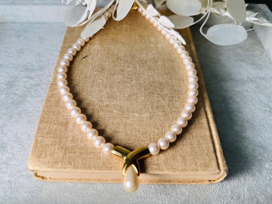 This vintage Napier pearl pendant necklace is stunning. From the 1980s this necklace is sleek and interesting, featuring 8mm cream pearls with a gold twist and cream pearl teardrop pendant. Fold over clasp with Napier signature. Would look beautiful on a bride or stacked with some chains for a modern spin. In excellent vintage condition.