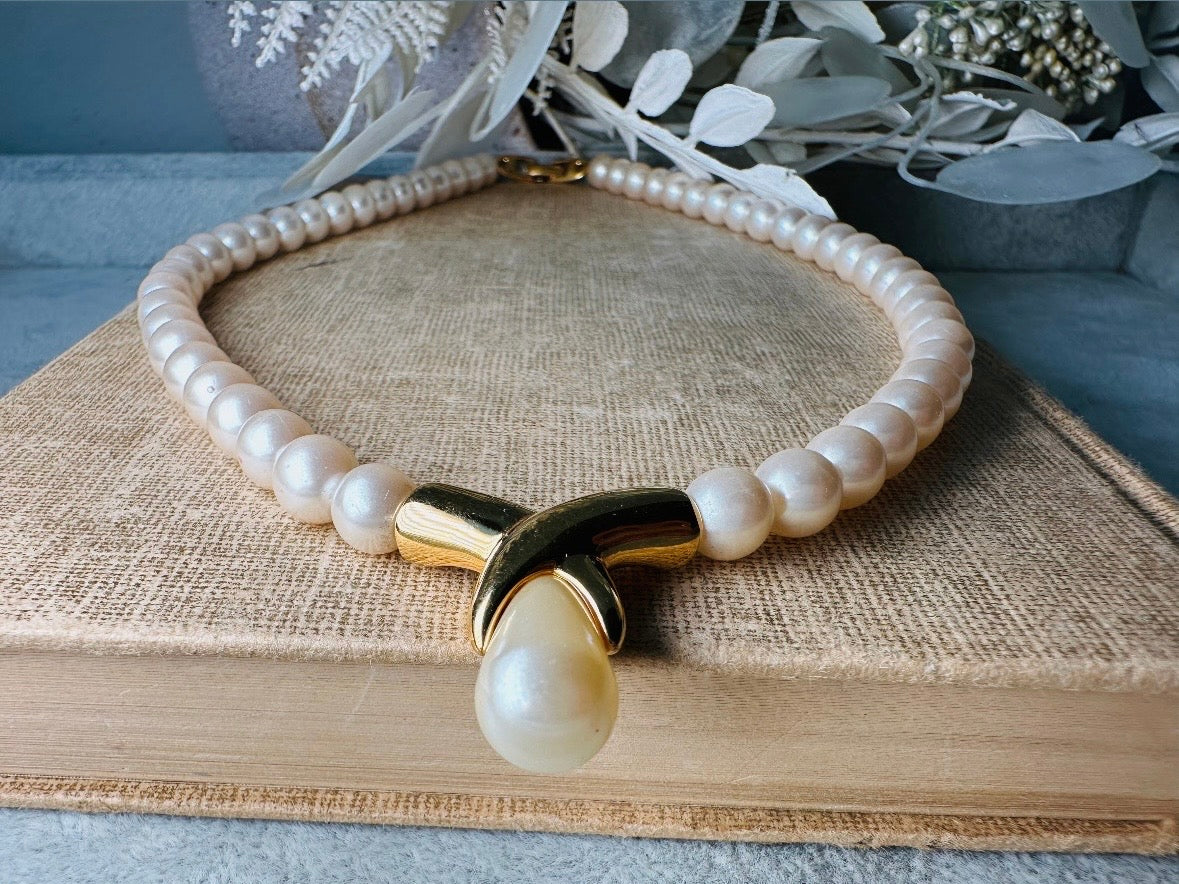 This vintage Napier pearl pendant necklace is stunning. From the 1980s this necklace is sleek and interesting, featuring 8mm cream pearls with a gold twist and cream pearl teardrop pendant. Fold over clasp with Napier signature. Would look beautiful on a bride or stacked with some chains for a modern spin. In excellent vintage condition.