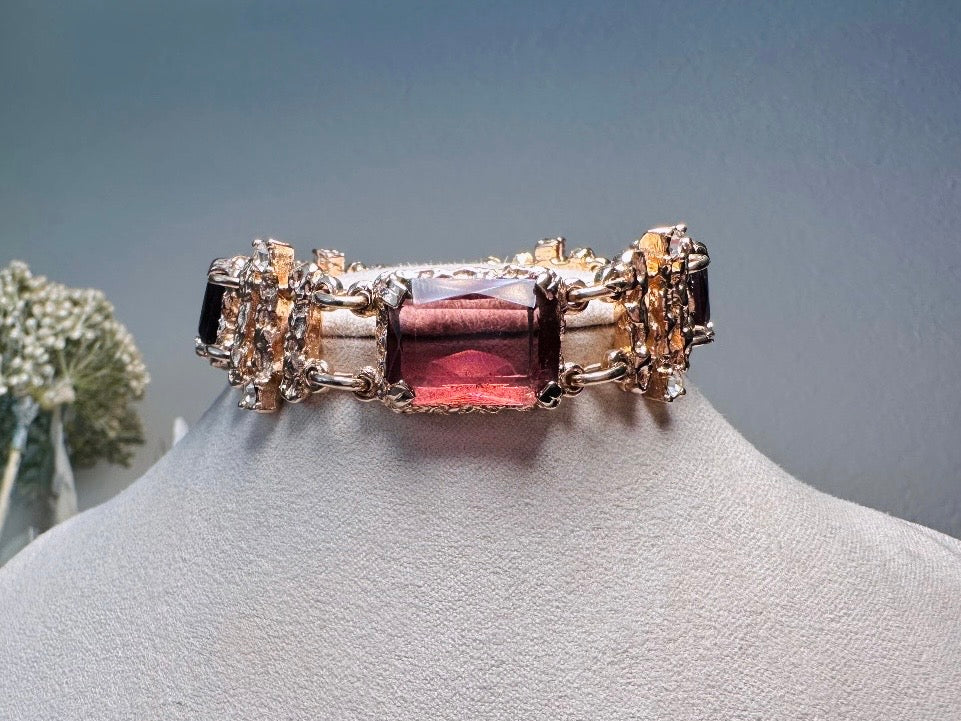 This 1970s faux amethyst vintage statement bracelet is gorgeous. Featuring three large smoky purple amethyst emerald cut stones prong set in gold. The setting is absolutely gorgeous in it's molten details- with a framed backing so the light can reflect through. Between each stone are golden branches in a brutalist style with small crystal accents. Absolutely beautiful vintage piece. Marked Sarah Coventry from 1973 Twilight collection.