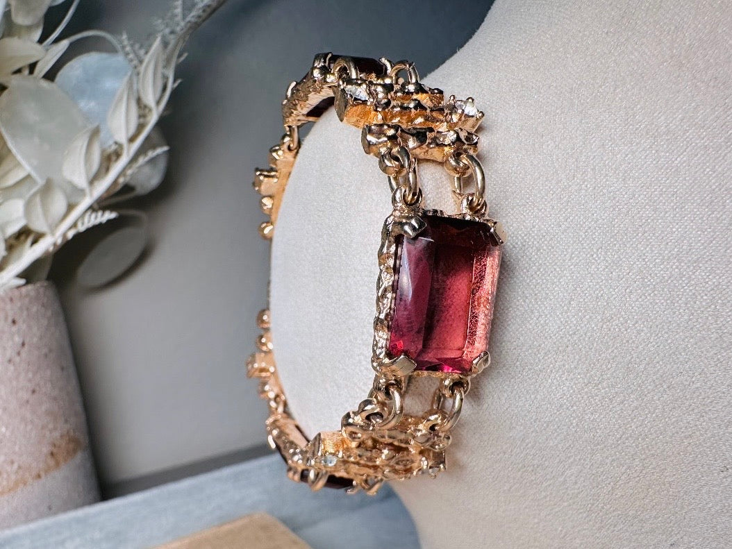 This 1970s faux amethyst vintage statement bracelet is gorgeous. Featuring three large smoky purple amethyst emerald cut stones prong set in gold. The setting is absolutely gorgeous in it's molten details- with a framed backing so the light can reflect through. Between each stone are golden branches in a brutalist style with small crystal accents. Absolutely beautiful vintage piece. Marked Sarah Coventry from 1973 Twilight collection.