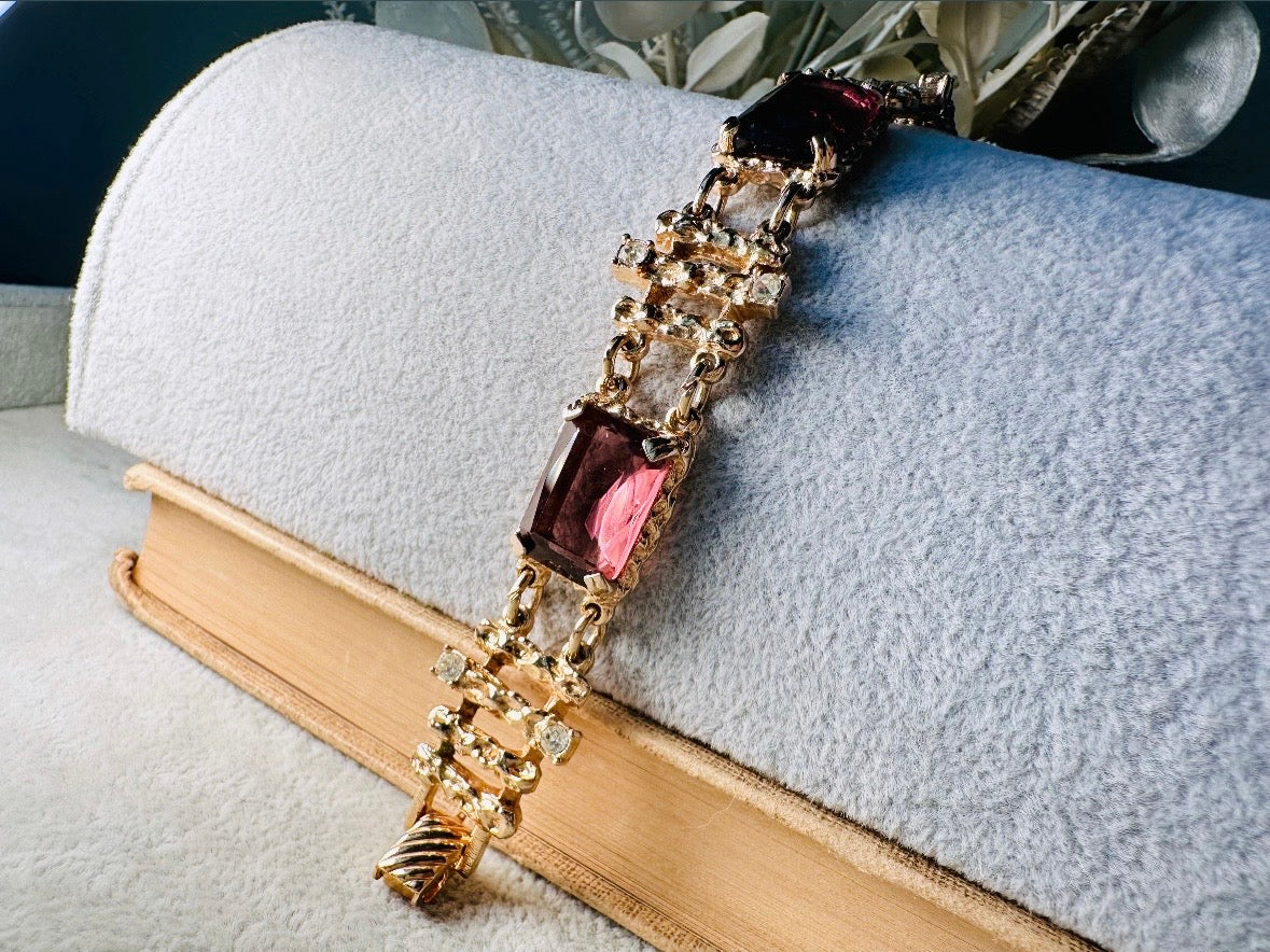 This 1970s faux amethyst vintage statement bracelet is gorgeous. Featuring three large smoky purple amethyst emerald cut stones prong set in gold. The setting is absolutely gorgeous in it's molten details- with a framed backing so the light can reflect through. Between each stone are golden branches in a brutalist style with small crystal accents. Absolutely beautiful vintage piece. Marked Sarah Coventry from 1973 Twilight collection.