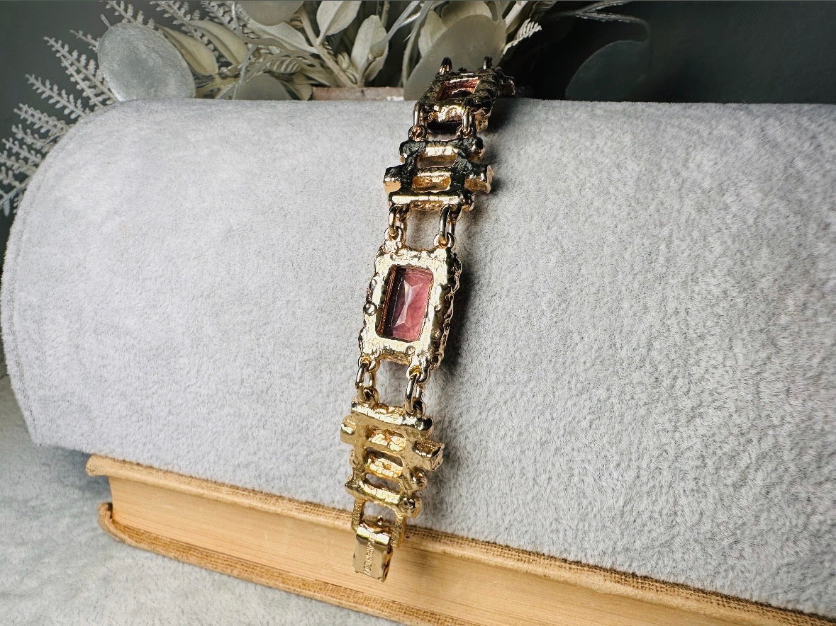 This 1970s faux amethyst vintage statement bracelet is gorgeous. Featuring three large smoky purple amethyst emerald cut stones prong set in gold. The setting is absolutely gorgeous in it's molten details- with a framed backing so the light can reflect through. Between each stone are golden branches in a brutalist style with small crystal accents. Absolutely beautiful vintage piece. Marked Sarah Coventry from 1973 Twilight collection.