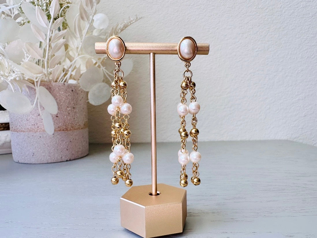 A pair of elegant vintage Trifari pearl chandelier earrings from the 1980s. These signed Trifari designer vintage earrings feature a cream pearl oval framed in gold as the post with a cascade of delicate long fine gold chain tassels with pearl links. In excellent vintage condition, they are three inches long.