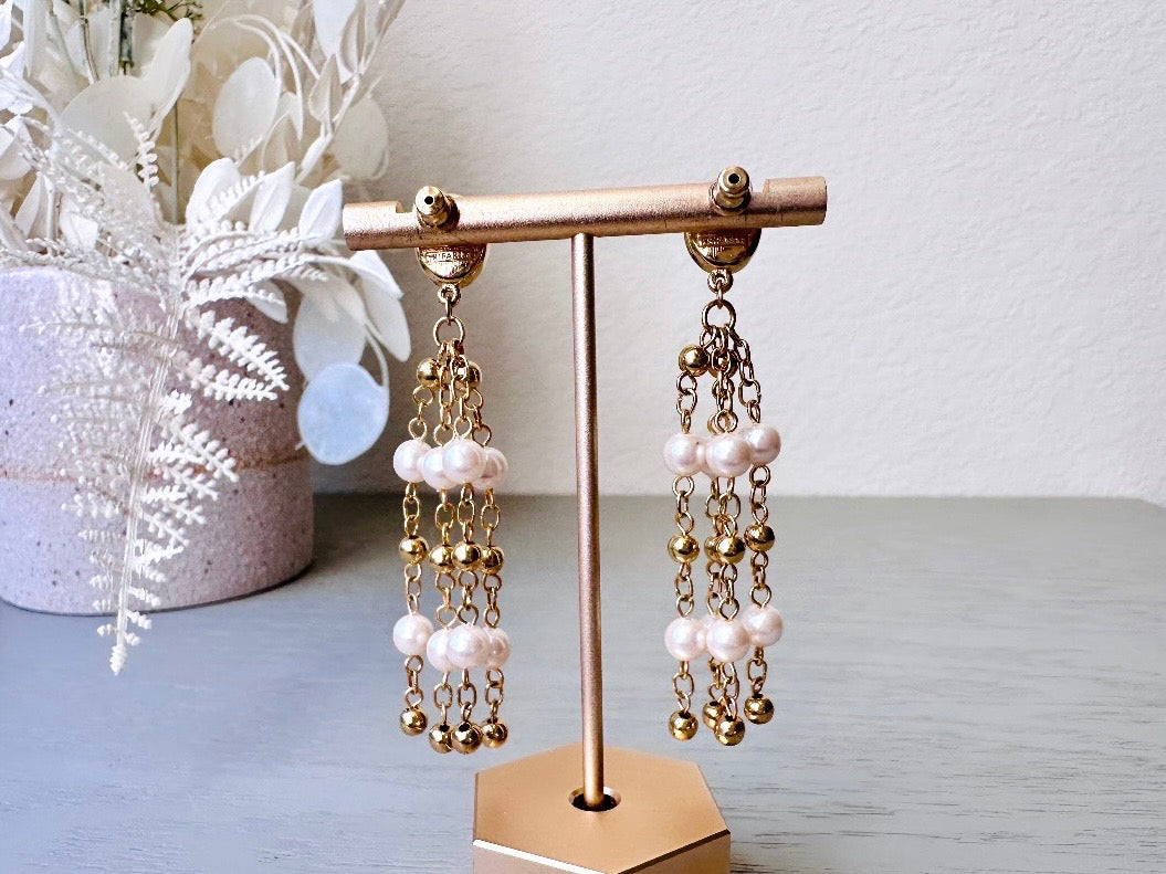 A pair of elegant vintage Trifari pearl chandelier earrings from the 1980s. These signed Trifari designer vintage earrings feature a cream pearl oval framed in gold as the post with a cascade of delicate long fine gold chain tassels with pearl links. In excellent vintage condition, they are three inches long.