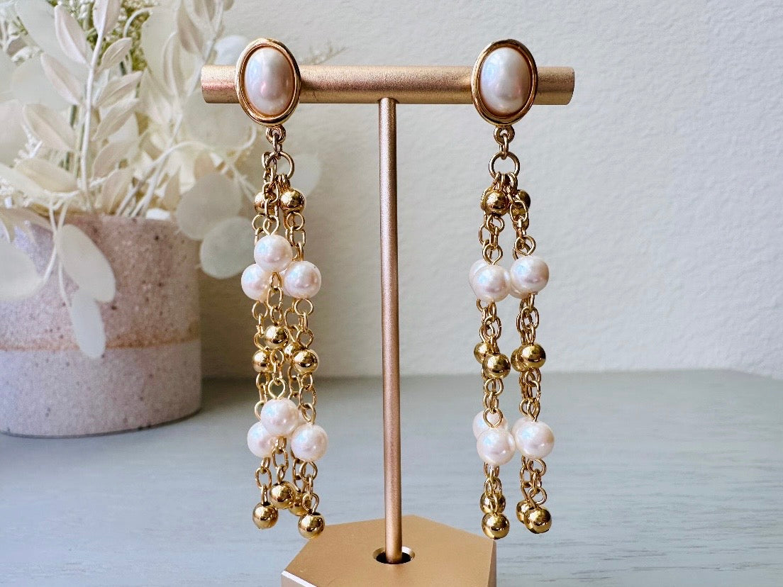A pair of elegant vintage Trifari pearl chandelier earrings from the 1980s. These signed Trifari designer vintage earrings feature a cream pearl oval framed in gold as the post with a cascade of delicate long fine gold chain tassels with pearl links. In excellent vintage condition, they are three inches long.