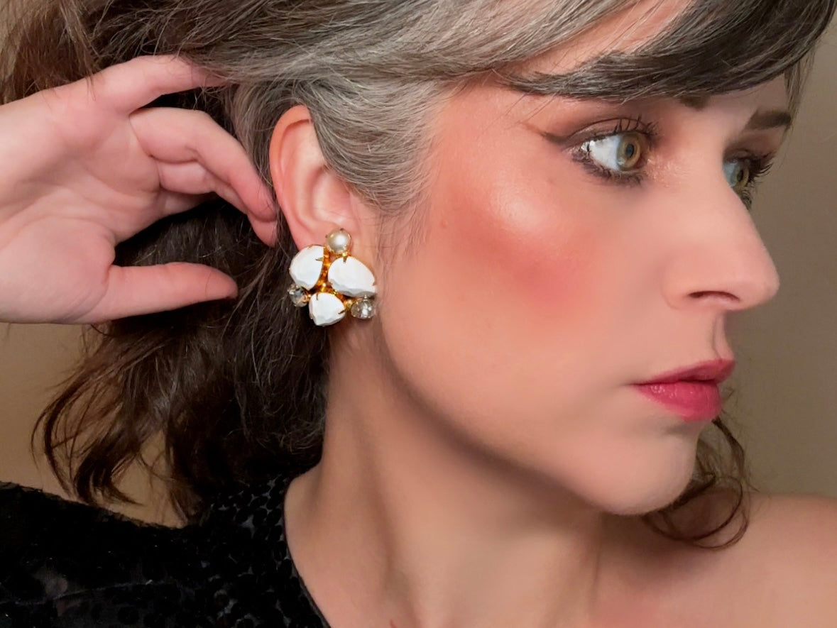 These vintage white earrings are an incredible pair of 1960s cluster earrings. Featuring opaque white faceted pear shaped stones, glass pearls and diamond rhinestones, these gold plated clip on earrings are fantastic. Each stone is prong set in a geometric pattern that mirrors each earring. A show-stopping rare pair of vintage earrings for a cocktail reception, award ceremony or wedding. Excellent vintage condition, please view all pics.