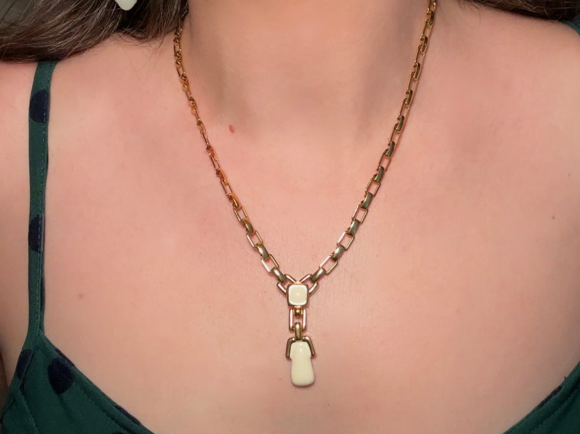 This vintage gold chain Y necklace by Monet is a rare find. Featuring flat link cable chain with a geometric drop pendant with cream enamel accents. This signed vintage necklace is from the 1970s at a peak time for Monet designs. This classic necklace is in excellent condition and just as classic today as it was when it debuted. Adjustable length with a hook closure. 