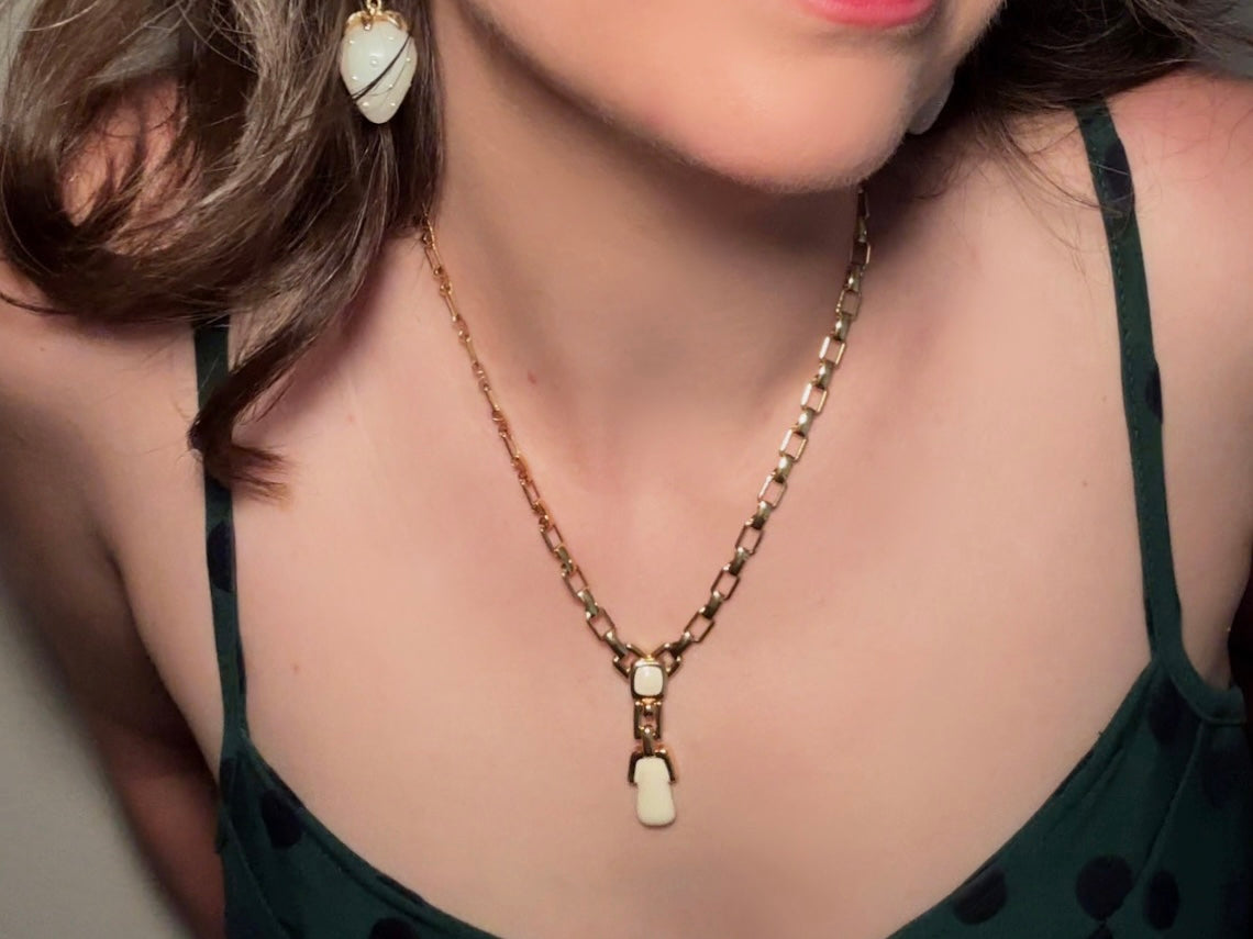 This vintage gold chain Y necklace by Monet is a rare find. Featuring flat link cable chain with a geometric drop pendant with cream enamel accents. This signed vintage necklace is from the 1970s at a peak time for Monet designs. This classic necklace is in excellent condition and just as classic today as it was when it debuted. Adjustable length with a hook closure. 