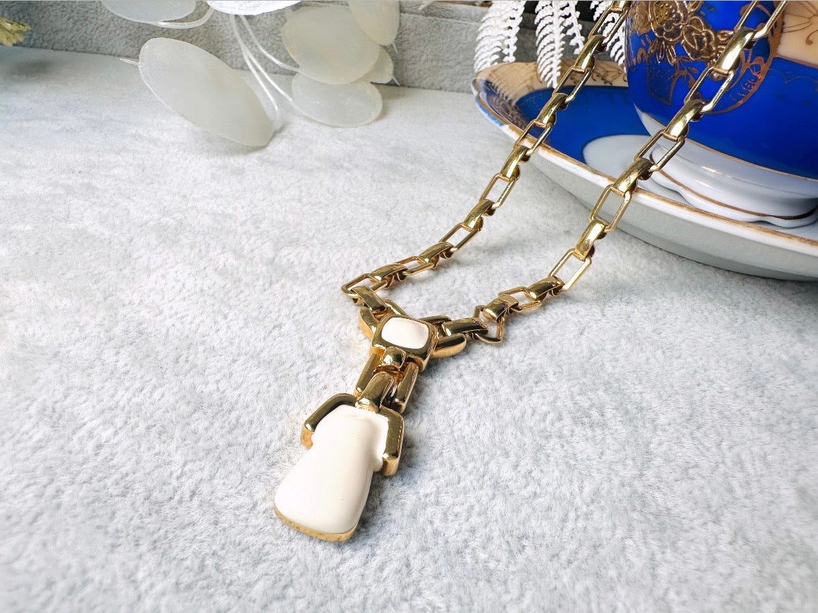 This vintage gold chain Y necklace by Monet is a rare find. Featuring flat link cable chain with a geometric drop pendant with cream enamel accents. This signed vintage necklace is from the 1970s at a peak time for Monet designs. This classic necklace is in excellent condition and just as classic today as it was when it debuted. Adjustable length with a hook closure. 