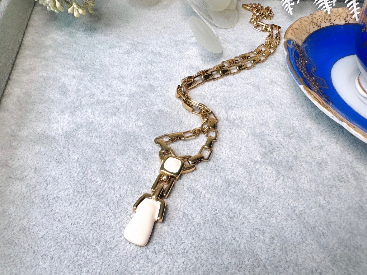 This vintage gold chain Y necklace by Monet is a rare find. Featuring flat link cable chain with a geometric drop pendant with cream enamel accents. This signed vintage necklace is from the 1970s at a peak time for Monet designs. This classic necklace is in excellent condition and just as classic today as it was when it debuted. Adjustable length with a hook closure. 