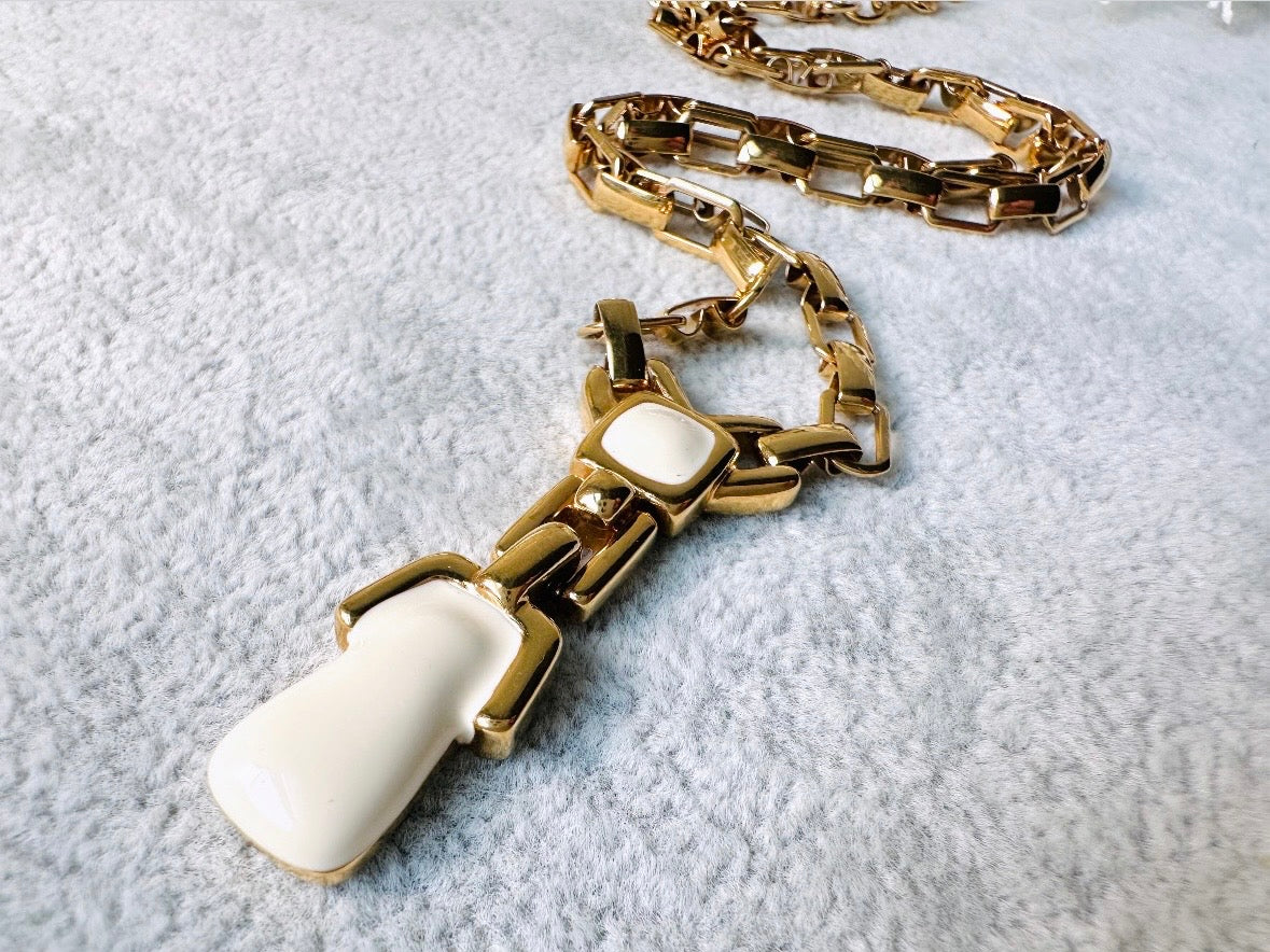 This vintage gold chain Y necklace by Monet is a rare find. Featuring flat link cable chain with a geometric drop pendant with cream enamel accents. This signed vintage necklace is from the 1970s at a peak time for Monet designs. This classic necklace is in excellent condition and just as classic today as it was when it debuted. Adjustable length with a hook closure. 