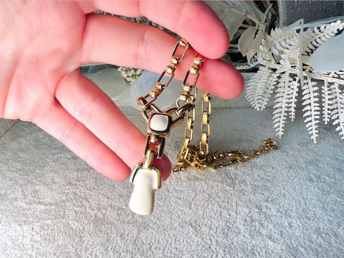 This vintage gold chain Y necklace by Monet is a rare find. Featuring flat link cable chain with a geometric drop pendant with cream enamel accents. This signed vintage necklace is from the 1970s at a peak time for Monet designs. This classic necklace is in excellent condition and just as classic today as it was when it debuted. Adjustable length with a hook closure. 