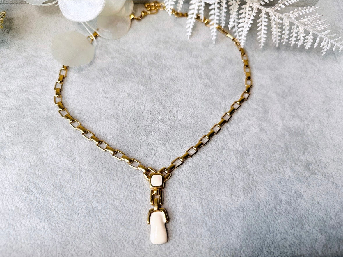 This vintage gold chain Y necklace by Monet is a rare find. Featuring flat link cable chain with a geometric drop pendant with cream enamel accents. This signed vintage necklace is from the 1970s at a peak time for Monet designs. This classic necklace is in excellent condition and just as classic today as it was when it debuted. Adjustable length with a hook closure. 