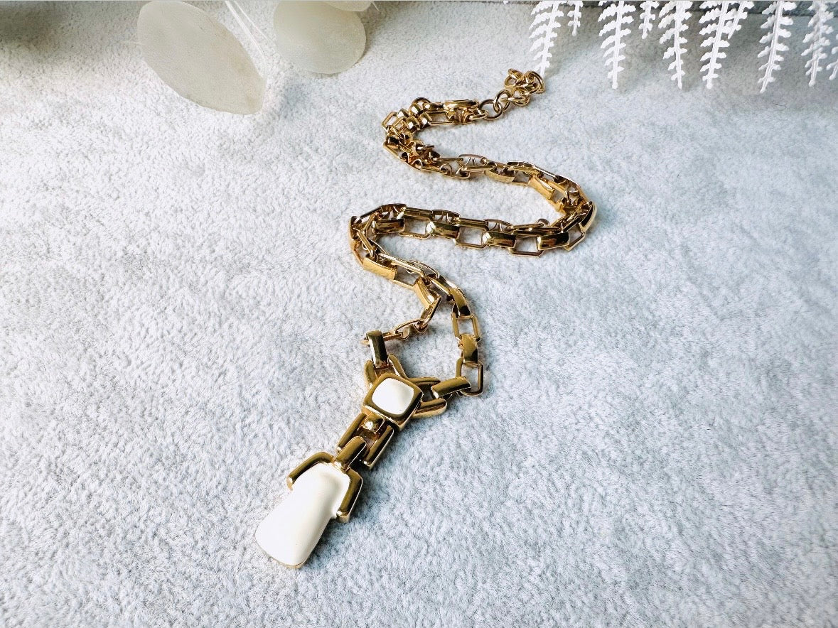 This vintage gold chain Y necklace by Monet is a rare find. Featuring flat link cable chain with a geometric drop pendant with cream enamel accents. This signed vintage necklace is from the 1970s at a peak time for Monet designs. This classic necklace is in excellent condition and just as classic today as it was when it debuted. Adjustable length with a hook closure. 