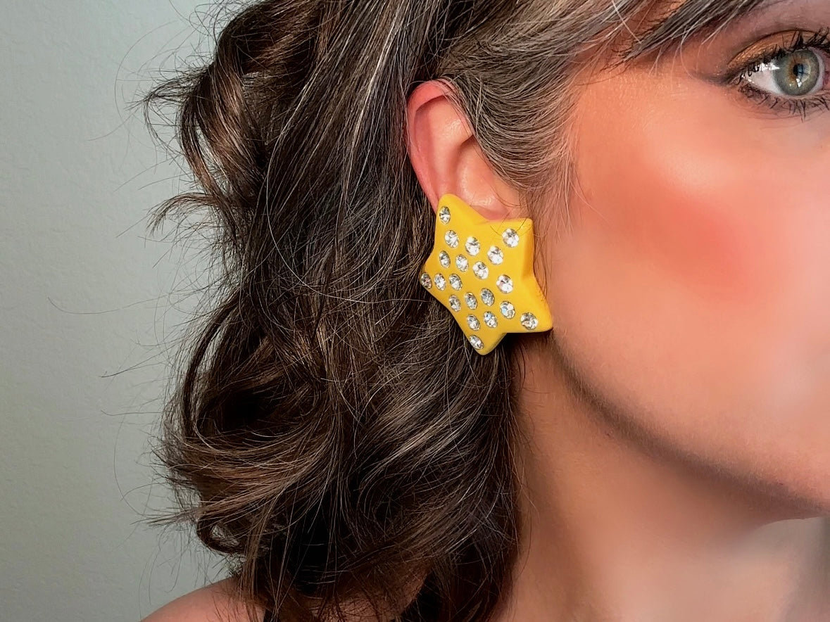 A pair of yellow star earrings from Piggle and Pop. A highly collectible pair of 1980s statement earrings. These yellow star earrings are bright banana yellow opaque lucite with diamond rhinestone accents. Huge vintage star clip ons with major rockstar vibes.