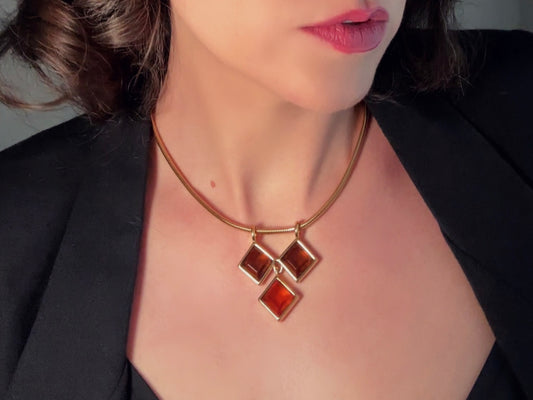 This  1970s Monet amber crystal necklace is a stunning designer vintage necklace. Featuring sleek gold snake chain with three dangling geometric faceted crystal pendant in amber and topaz, this 1970s topaz necklace is versatile and unique. Modelled by Bethan Jayne.